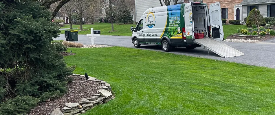 Manicured lawn near landscape bed and van parked in the street in Maxatawny, PA.