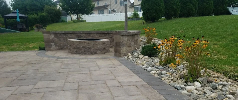 Patio area with fire pit and seating wall on a property in Bally, PA.