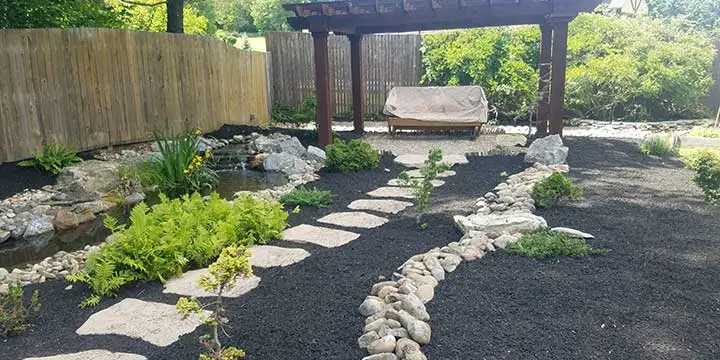 Landscape bed, water feature, and pergola installed at a East Greenville, PA home.
